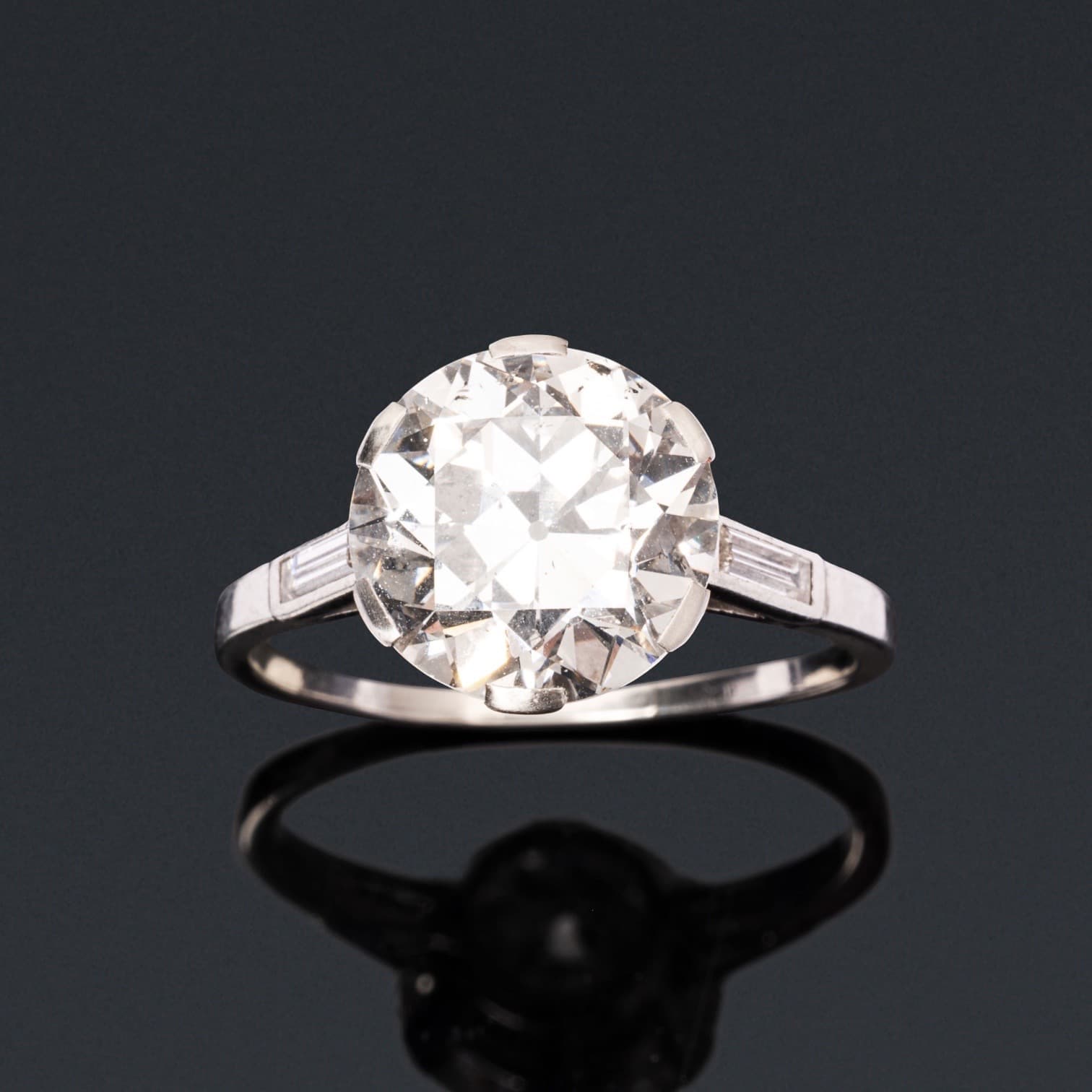 Bague solitaire en platine (850e), ornée d’un diamant demi-taille en serti griffe, épaulé de 2 diamants taille baguette.