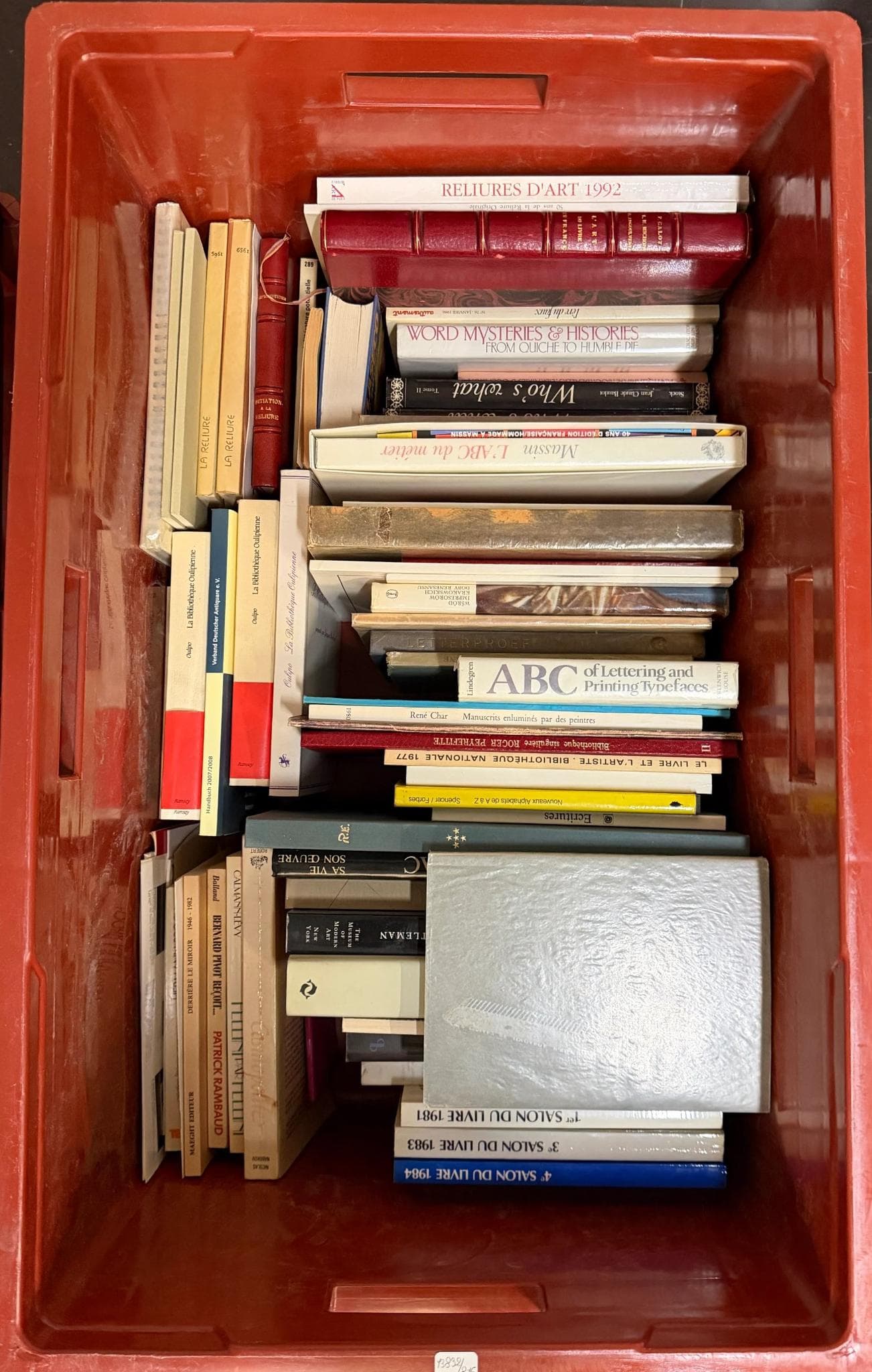 Technique littéraire. Caisse contenant un ensemble de volumes divers, principalement brochés ou cartonnés, comprenant des ouvrages sur la reliure, la typographie, l’histoire du livre, des catalogues d’expositions et des monographies, formats variés, certains exemplaires illustrés ou annotés.