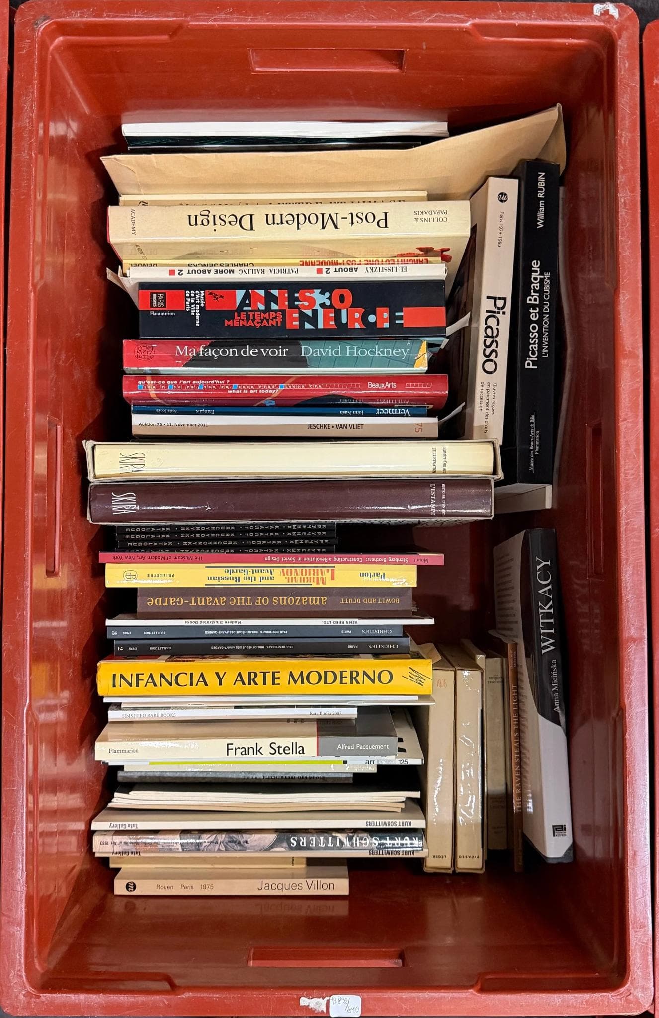 Livres d’art. Caisse contenant divers auteurs et titres visibles, principalement sur l’art moderne et contemporain, catalogues d’exposition, monographies et ouvrages illustrés, formats variés, brochés et cartonnés. Picasso, Hockney, Frank Stella, Witkacy, Jacques Villon, Infancia y arte moderno, Post-Modern Design, etc.