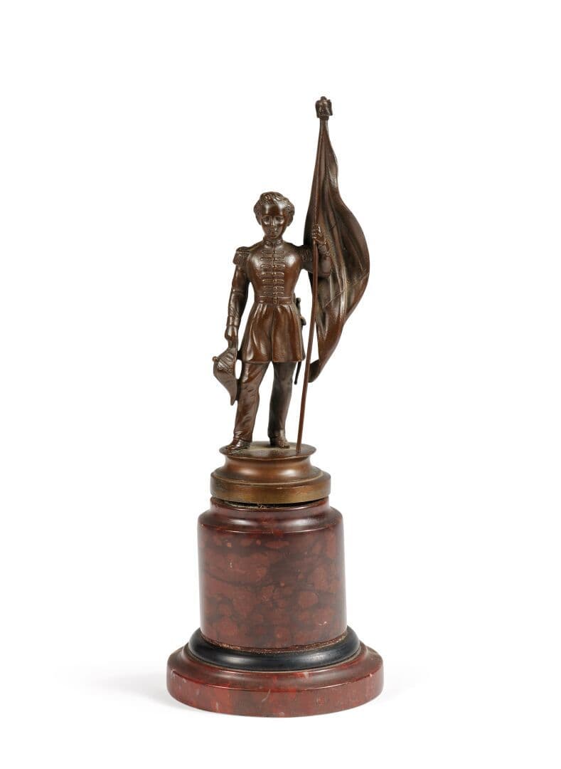 Louis-Napoléon BONAPARTE (1856-1879), fils de Napoléon III et Eugénie.Statuette en bronze à patine brune figurant le Prince Impérial enfant en pied, en uniforme militaire, tenant un drapeau de la main gauche et son bicorne de la droite.