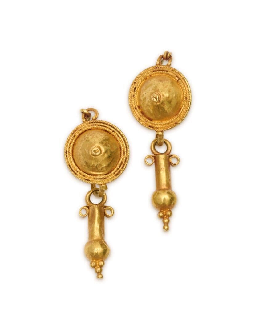 Paire de pendants d'oreilles en or, composé d'un disque bordé de trois rangées de filigranes, retenant un tube en pampille flanqué de volutes et terminé de granules.